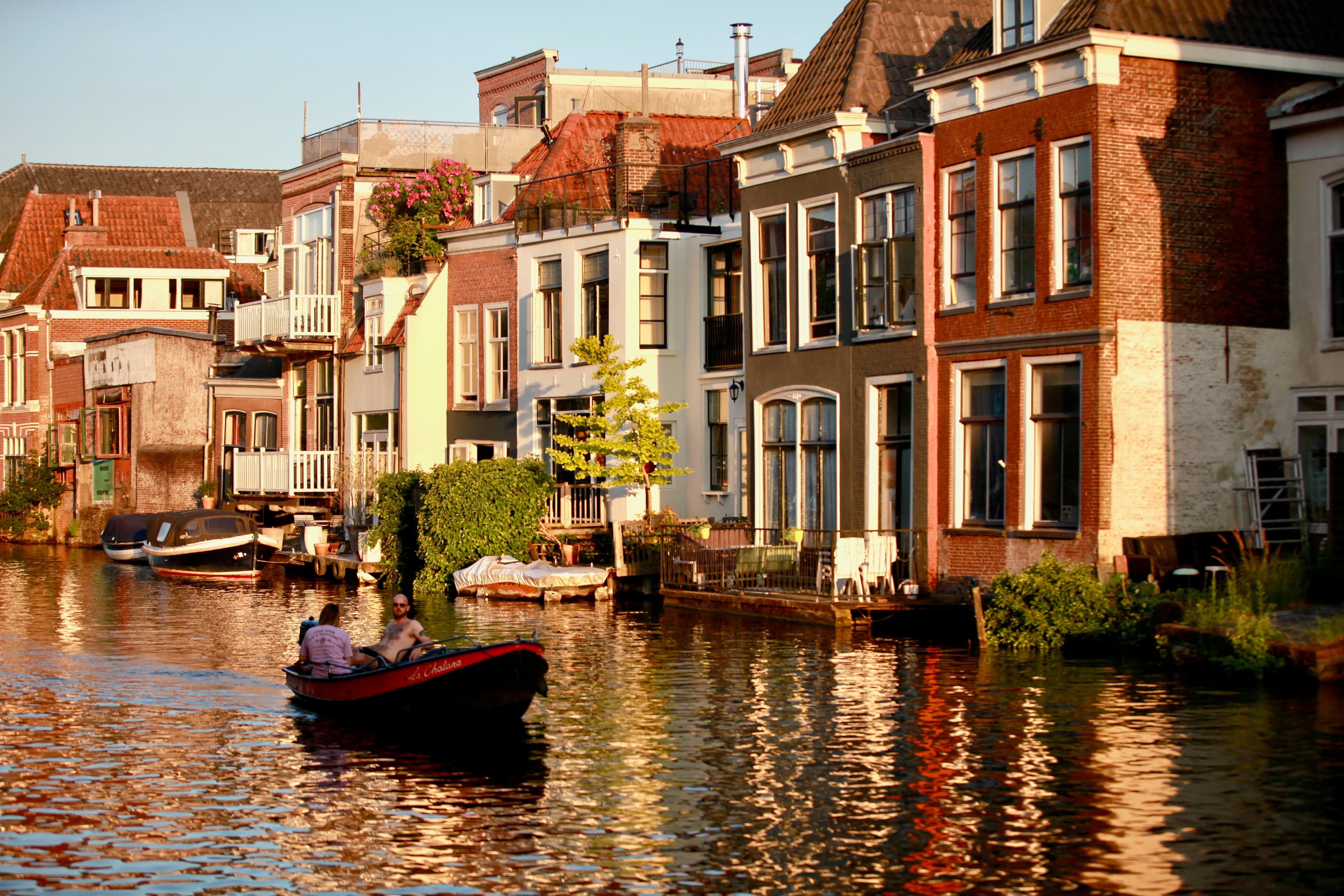 A boat passing warm-lit canal houses in Leiden