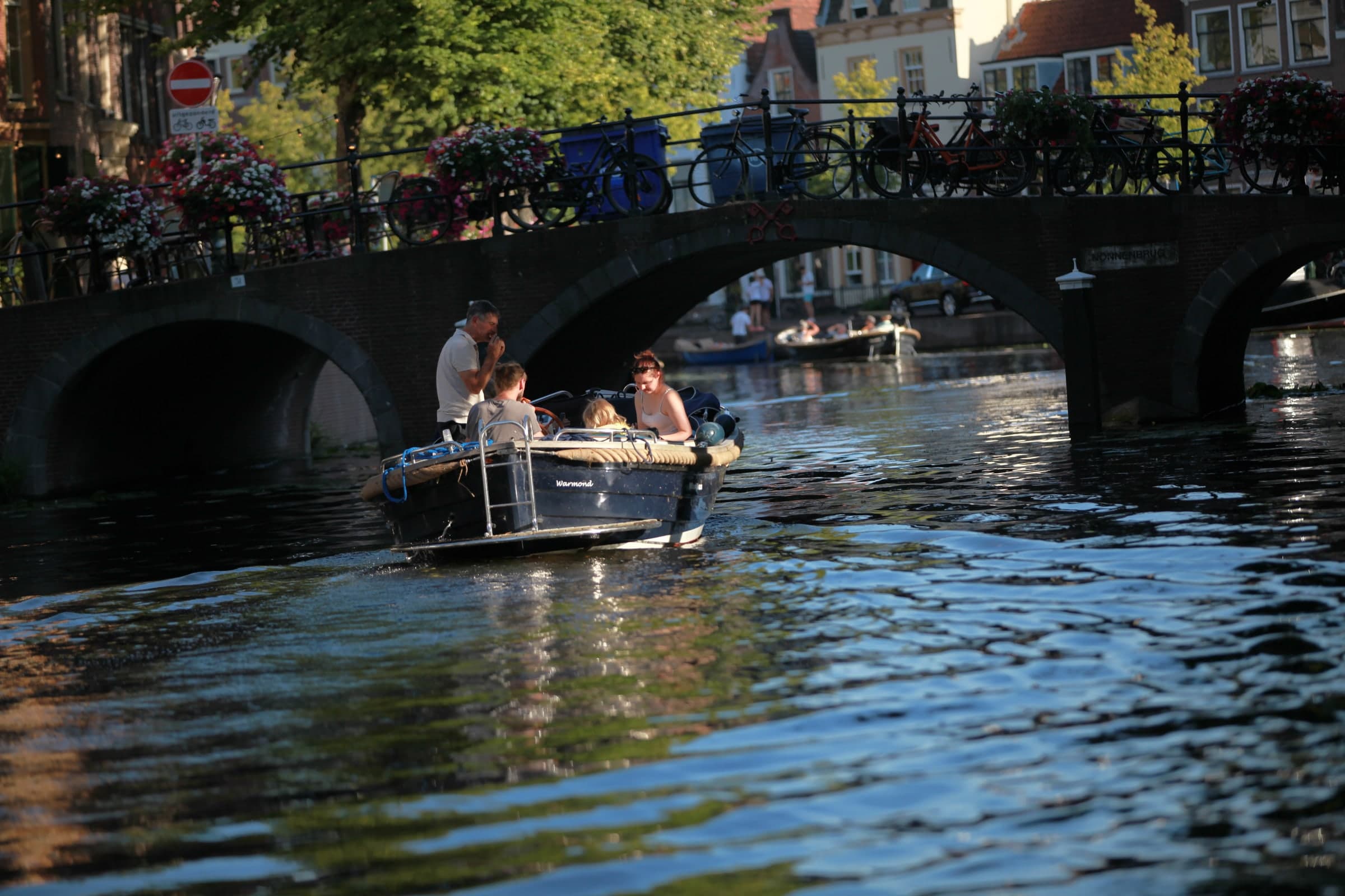 Canal boat passing beneath a stone bridge in Leiden