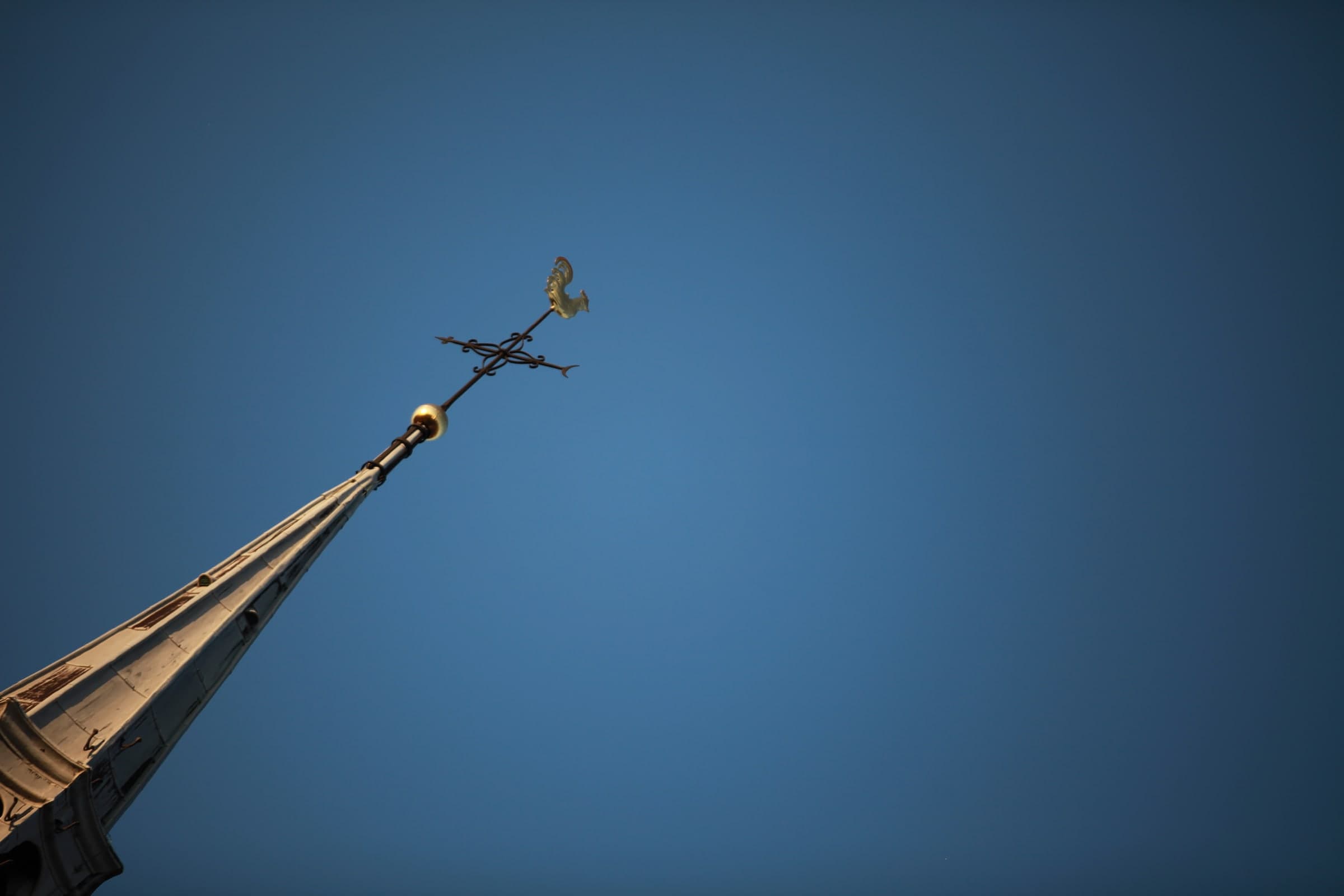 Church weather vane against blue sky in Leiden