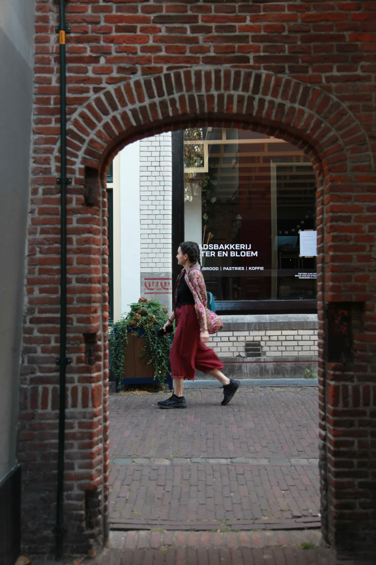 Woman crossing a brick archway in Leiden
