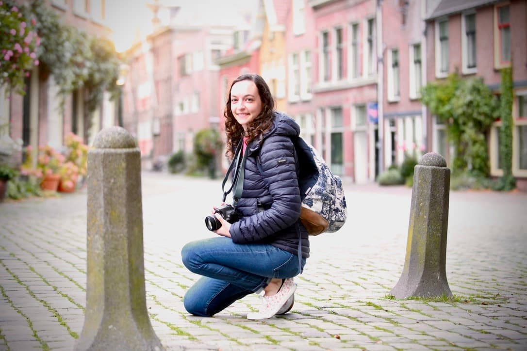A smiling participant holding a camera on a cobblestone street in Leiden